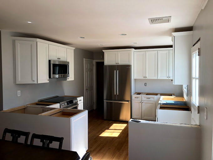 A kitchen with white cabinets and a silver refrigerator